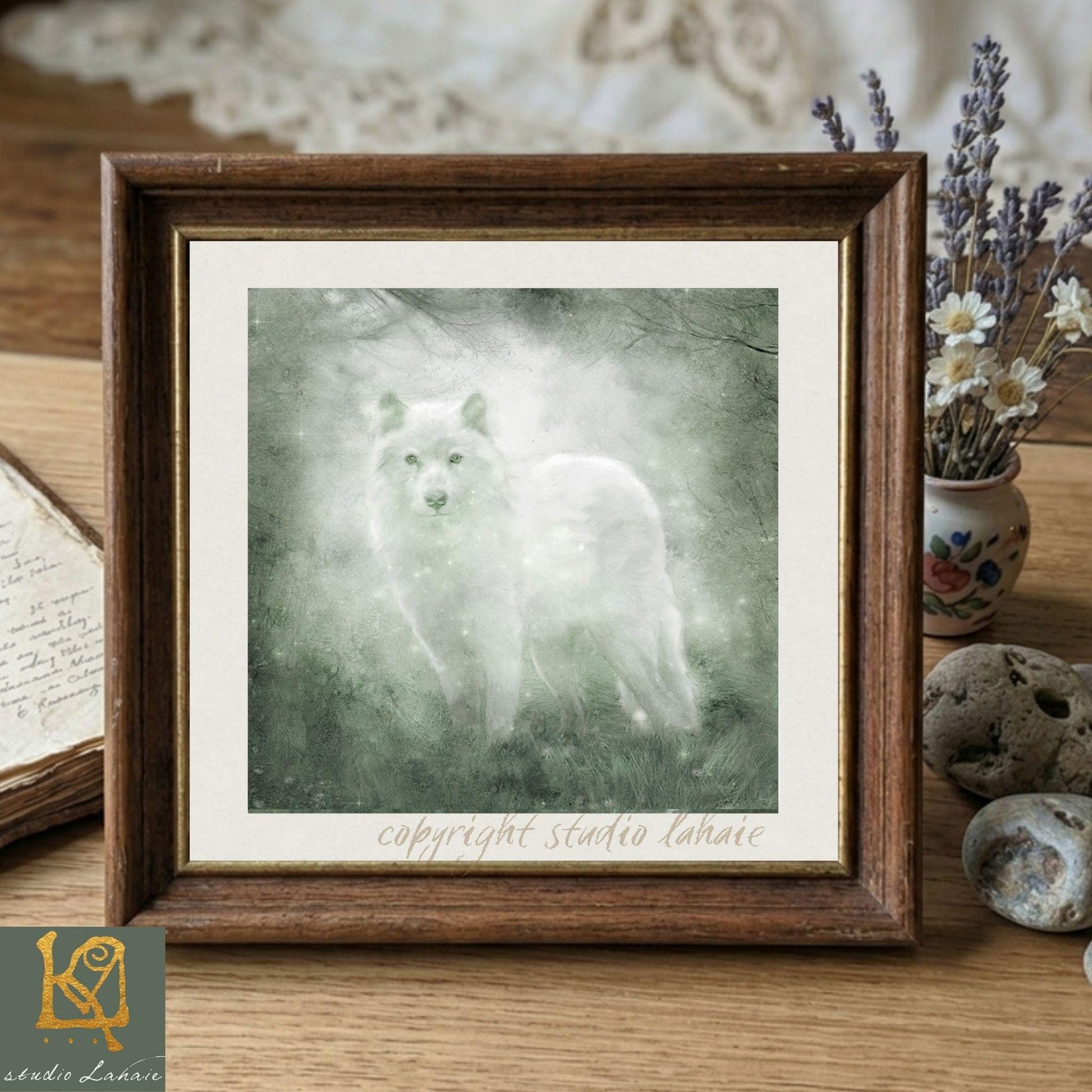 A framed painting of a white wolf standing in a forest, with a vase of flowers and a book on a wooden surface in the background.