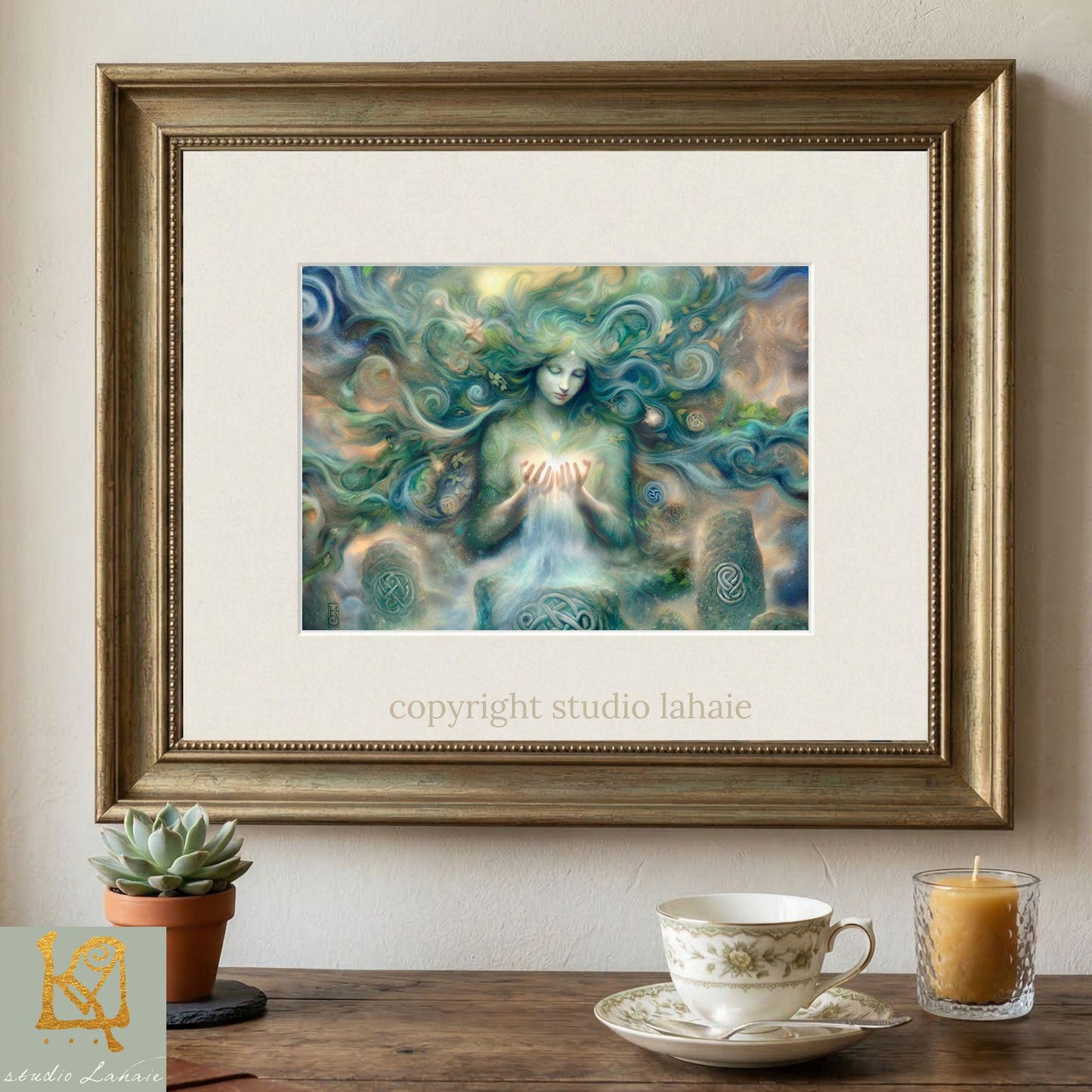a framed painting of a woman with flowing hair and a green, ethereal appearance, displayed on a wall above a wooden table with a teacup and a candle.