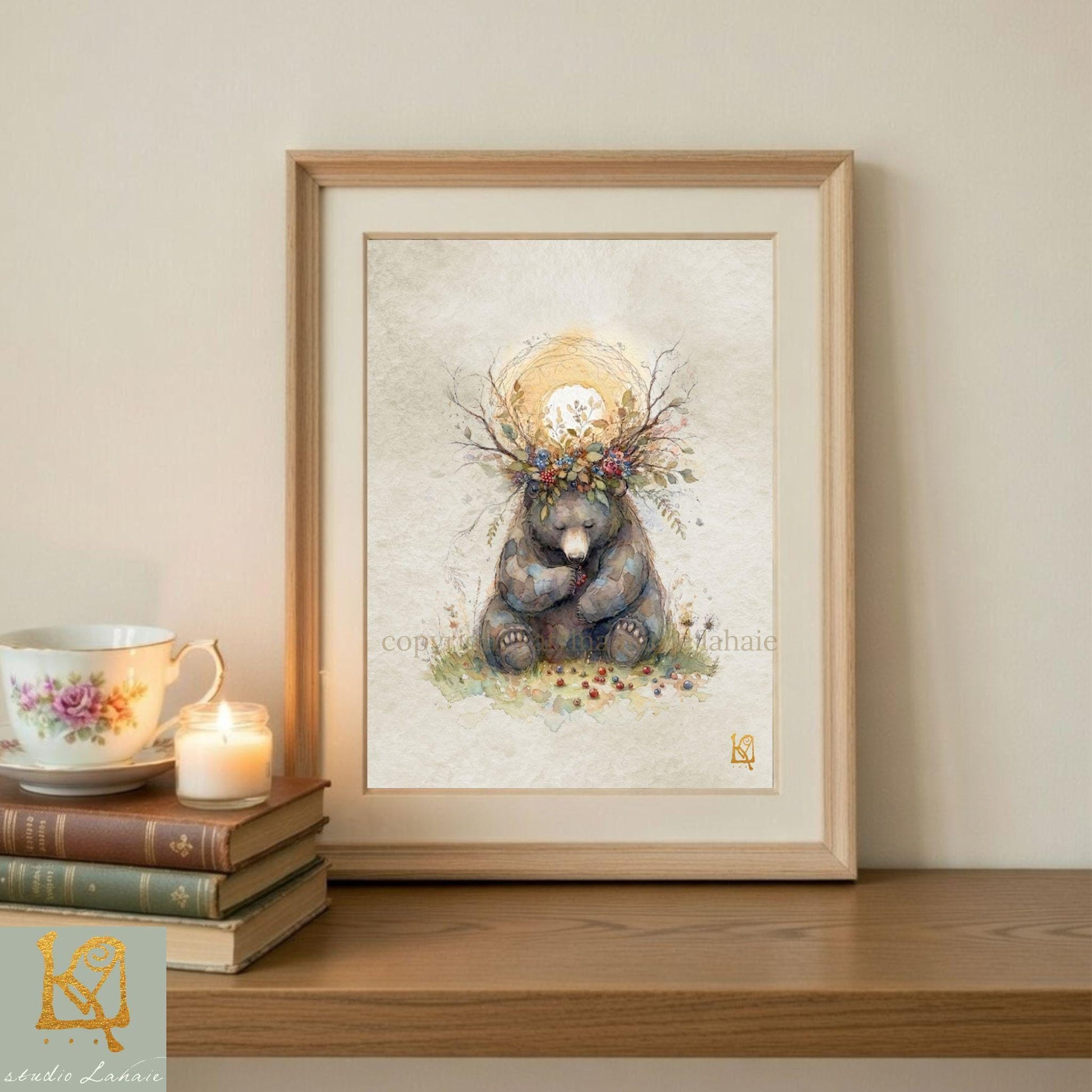 a framed painting of a bear sitting on a branch with flowers, placed on a wooden shelf next to a stack of books and a lit candle.